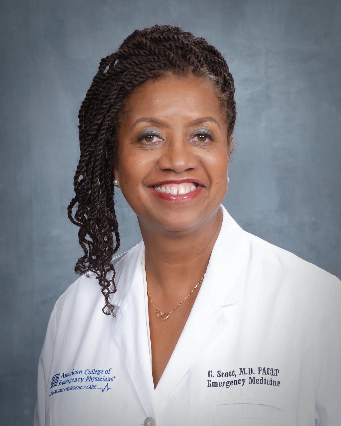 Dr. Scott in a white coat embroidered with her name and the American College of Emergency Physicians.